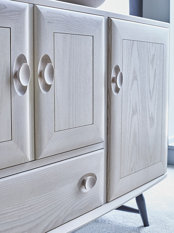 A close up of the doors of the Windsor cabinet in a light finish with black legs