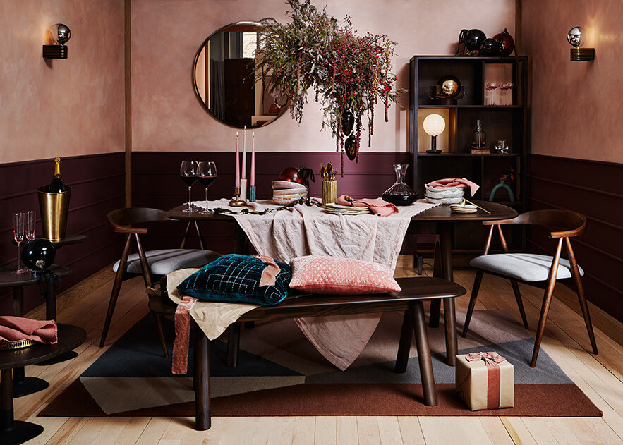A contemporary, luxurious dining room dressed for Christmas featuring dark ercol dining furniture and dressed in shades of pink and green
