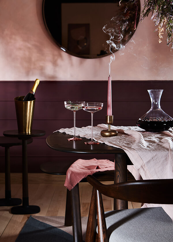 A recently extinguished candle smoking, sat on a Corso table alongside champagne glasses