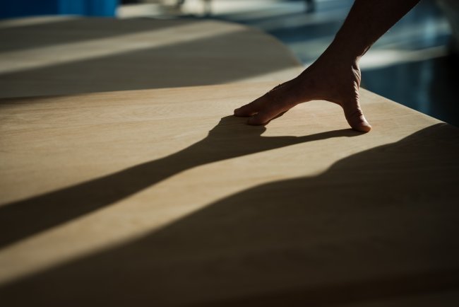 Hand touching the surface of an ercol table casting a long shadow